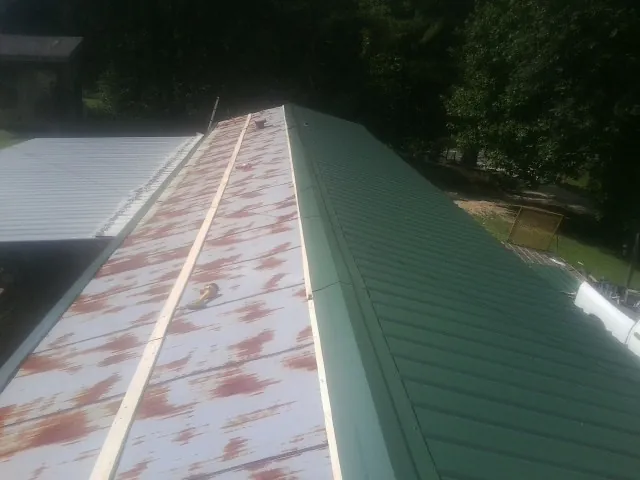 Old rusted panels beside newly installed green metal roofing — Wind Damage Roof Repair by Roofing Brothers in West Concord
