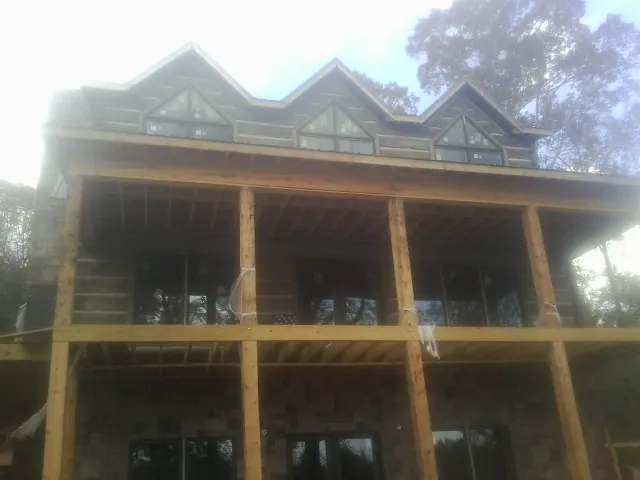 Dormers and porch framing on a large log home under construction — Roof Coating work by our crew in West Concord