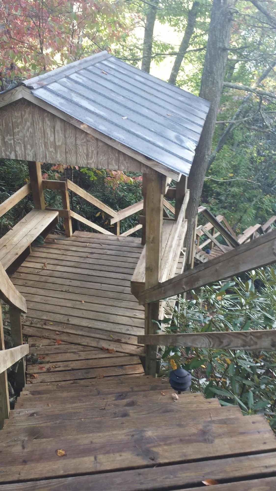 Metal roofed shelter over wooden steps on a wooded walkway — Skylight Repair & Installation work by our crew in West Concord