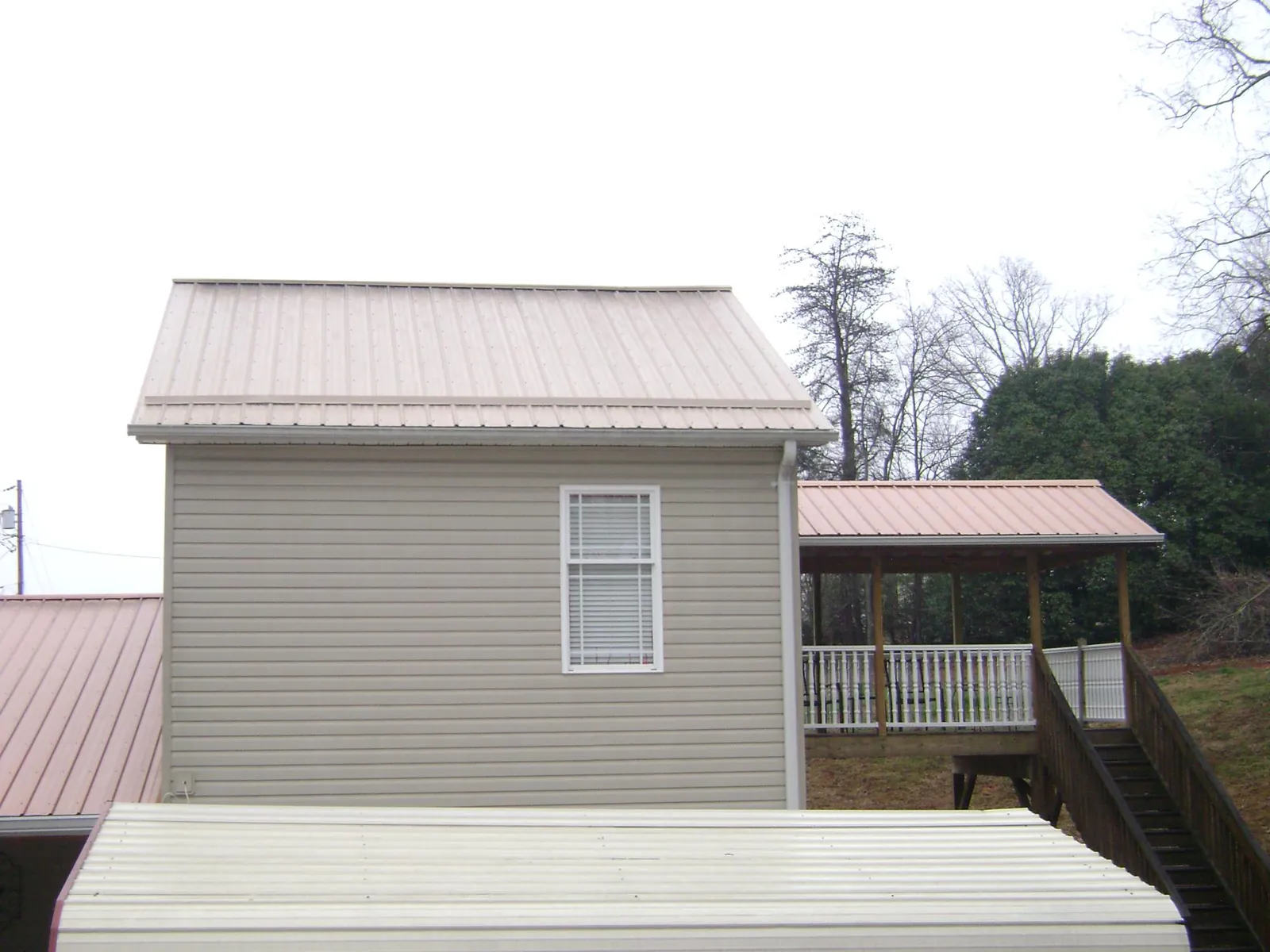 Tan metal roofs on a two story addition and attached porch, from a Roof Replacement job in West Concord