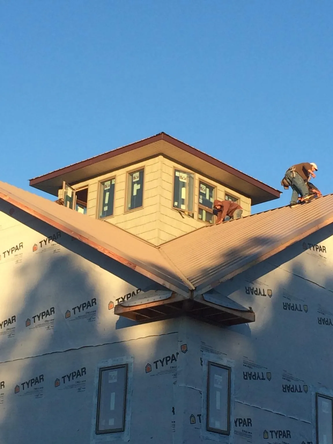 Roofers working around a rooftop cupola on a new metal roof at sunset — Roof Waterproofing in West Concord by Roofing Brothers